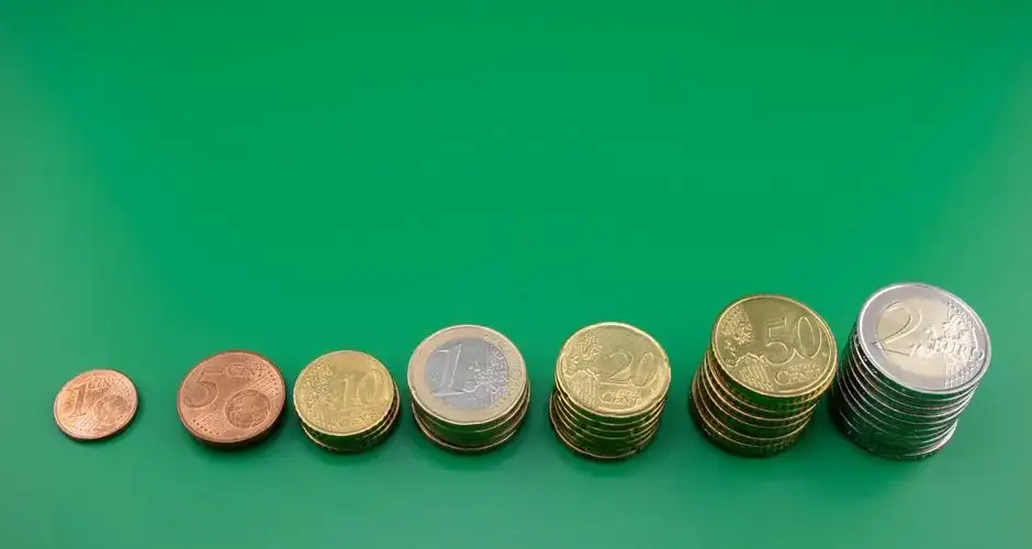 Various euro coins stacked incrementally on a vibrant green background.