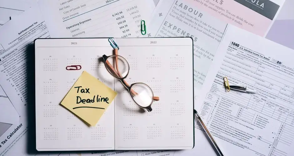 Overhead view of financial documents, planner, and glasses emphasizing tax deadline.