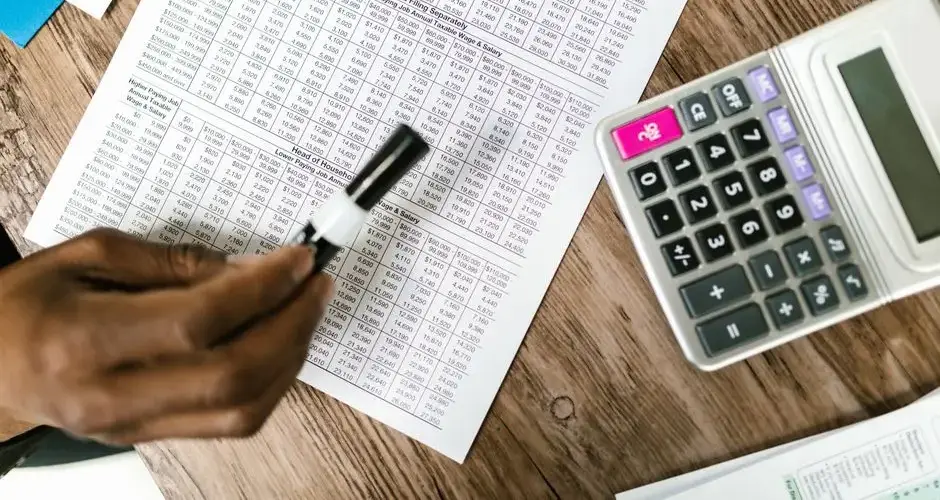 Close-up of tax documents and calculator on wooden table, highlighting financial analysis.