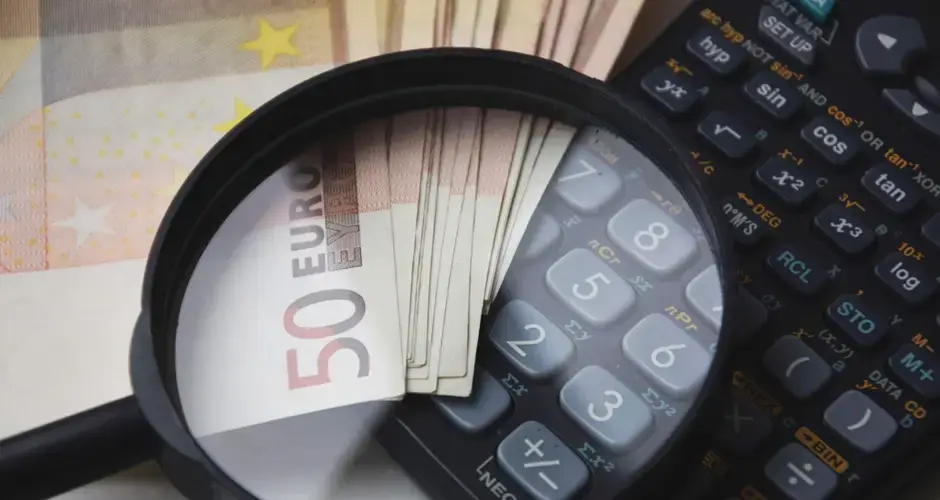 Euro bills under magnifying glass with calculator, symbolizing finance and analysis.