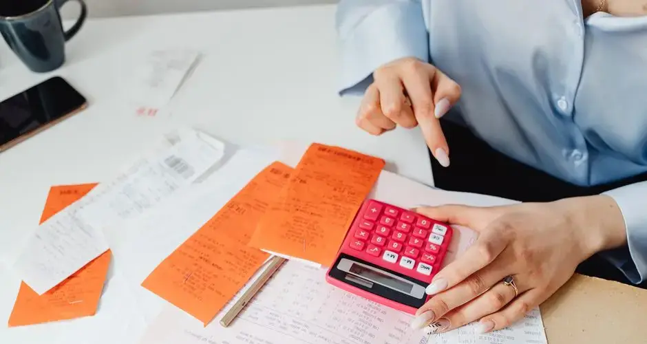 Businesswoman calculates expenses using receipts and calculator at desk. Ideal for finance, accounting themes.