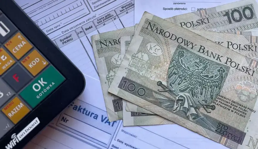 Polish currency placed on invoices with a calculator, illustrating financial transactions or budgeting.