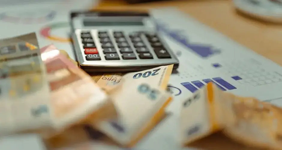 Euro banknotes and calculator on financial documents, focusing on business budget planning.
