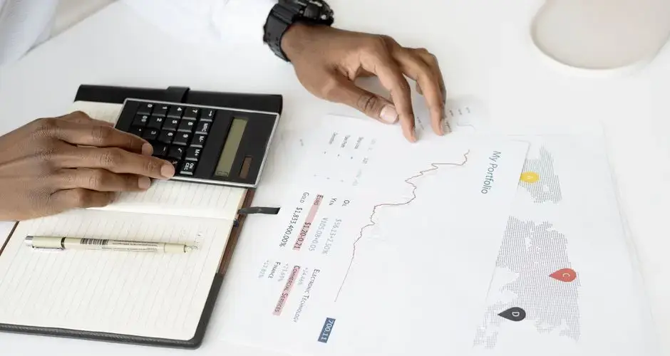 Overhead view of a person analyzing financial documents using a calculator for investment planning.