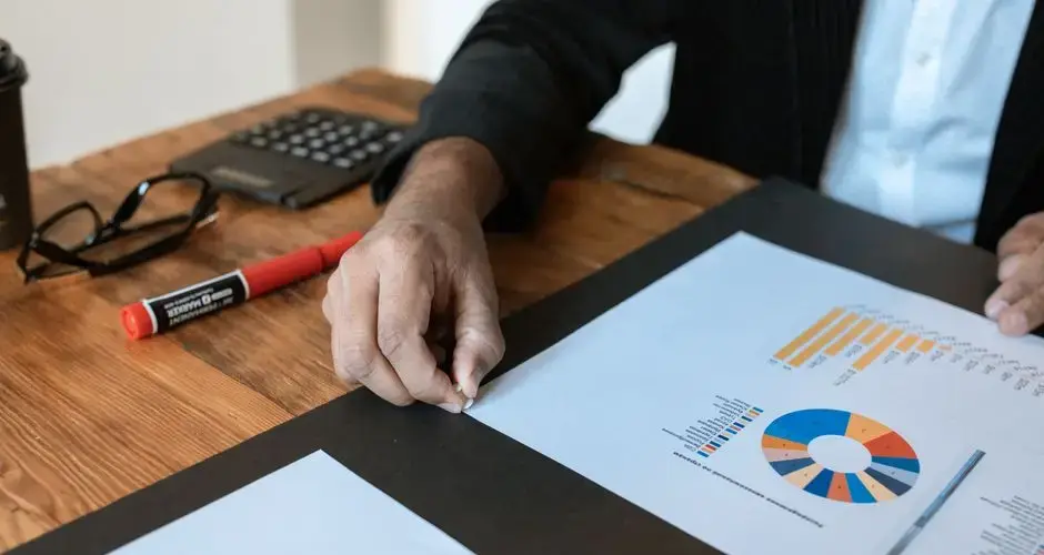 Close-up of a business setting with charts, documents, and a hand pointing.