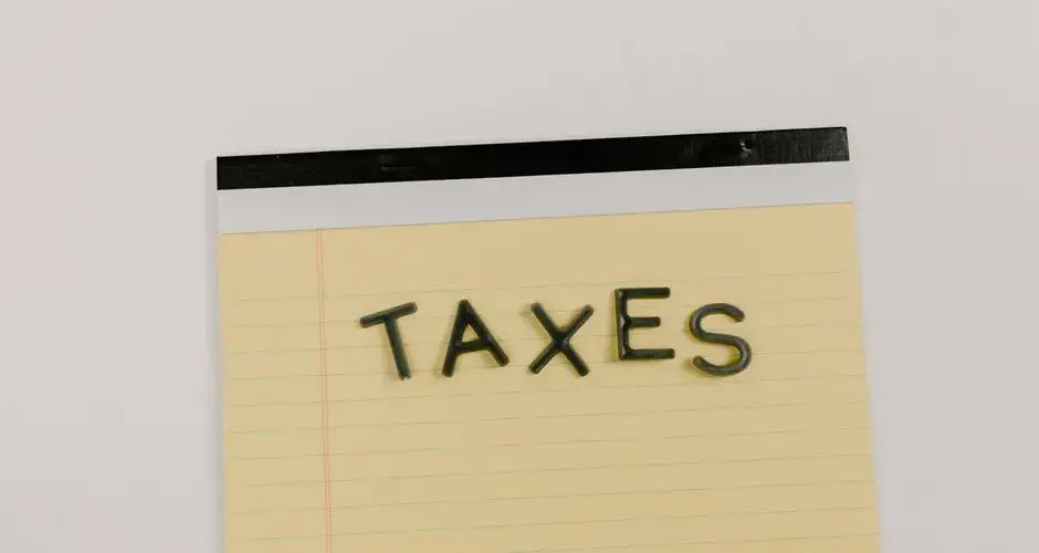 A flat lay of the word 'TAXES' on a yellow notepad, ideal for financial content.