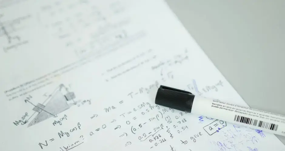 Close-up showing mathematical formulas and a marker on bond paper, ideal for education themes.
