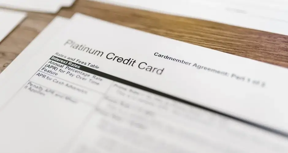Close-up of a platinum credit card agreement document on a wooden desk.