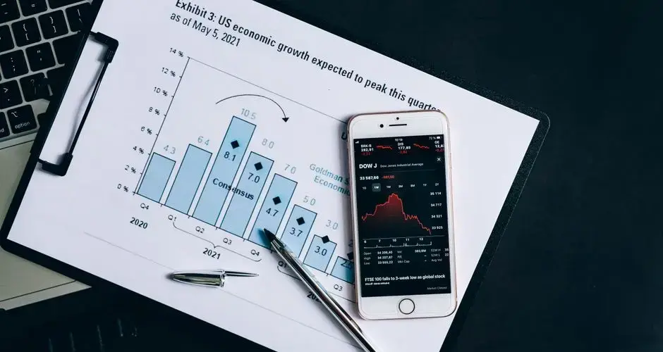 A smartphone displaying stock data rests on a financial report graph.