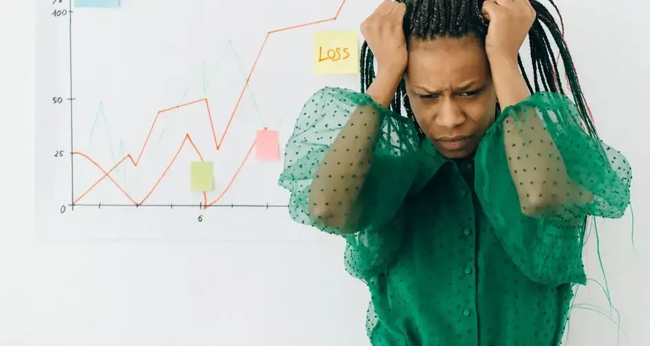 Frustrated businesswoman in green blouse analyzing a graph showing financial loss.