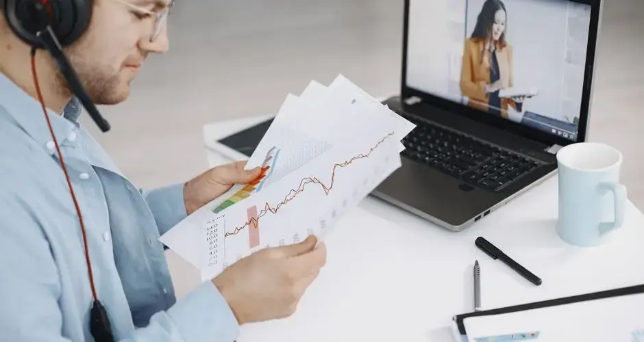 Business professional analyzing charts during a remote meeting with video call and headset.