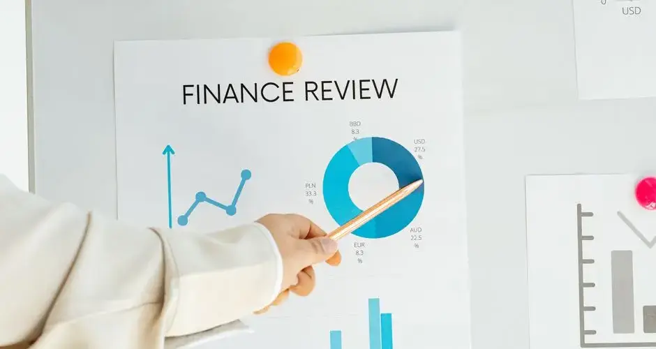 Close-up of hand pointing at finance report with charts and graphs on paper.