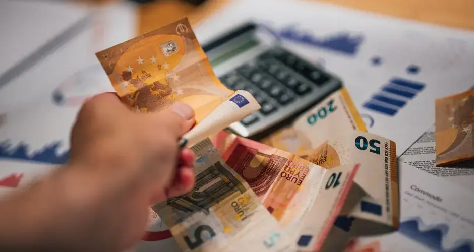 Close-up of Euro banknotes on financial documents and a calculator, depicting financial planning.