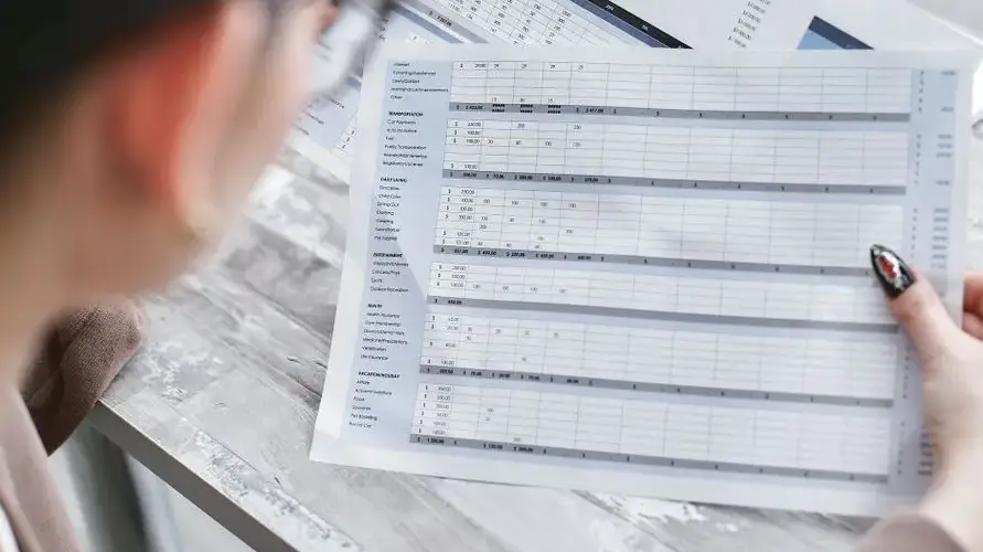 A businesswoman reviewing financial spreadsheets with charts and graphs in an office setting.
