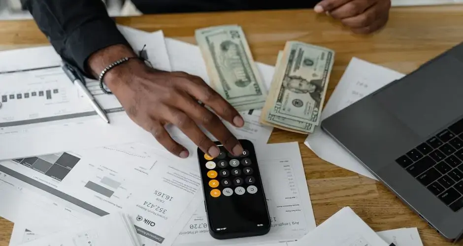 Overhead view of financial documents with calculator, cash, and laptop for financial planning.
