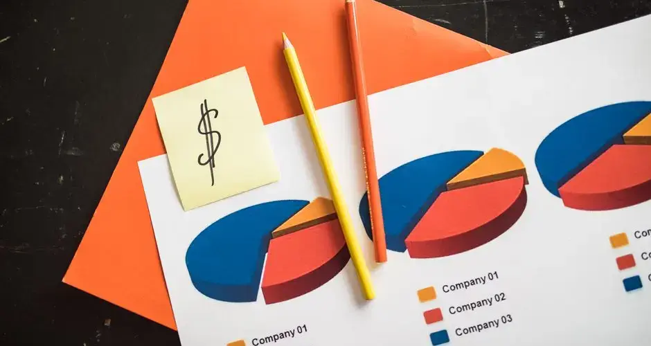 A creative arrangement of financial pie charts with colorful pencils and a dollar note, perfect for business themes.