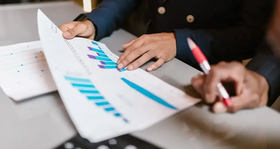 Close-up of professionals reviewing financial graphs at a business meeting.