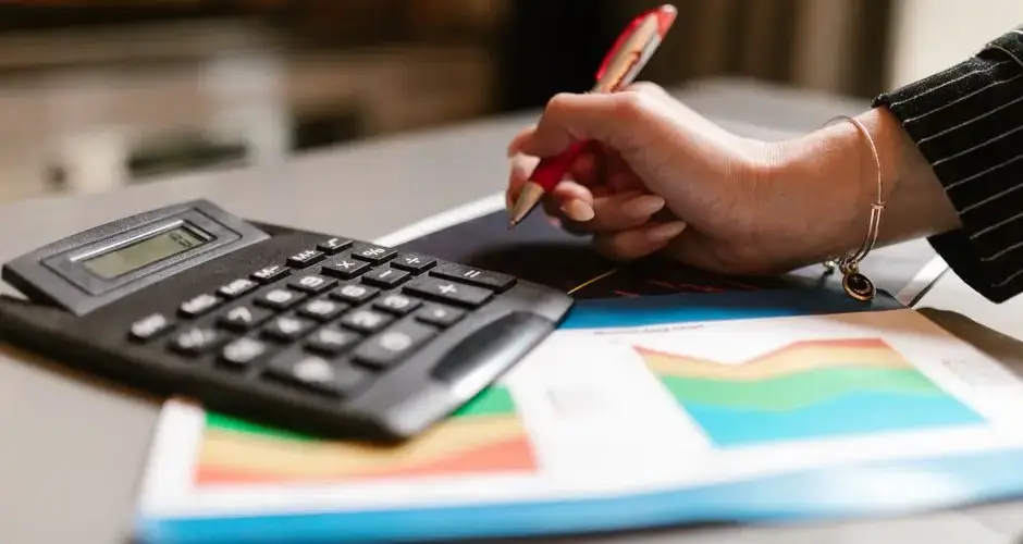 A business professional uses a calculator and documents during a workspace task.