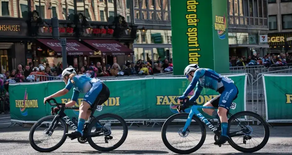 Dynamic scene of cyclists racing in Copenhagen with spectators and city backdrop.