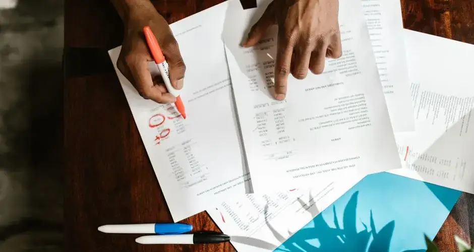 Overhead view of hands highlighting financial documents on a desk.