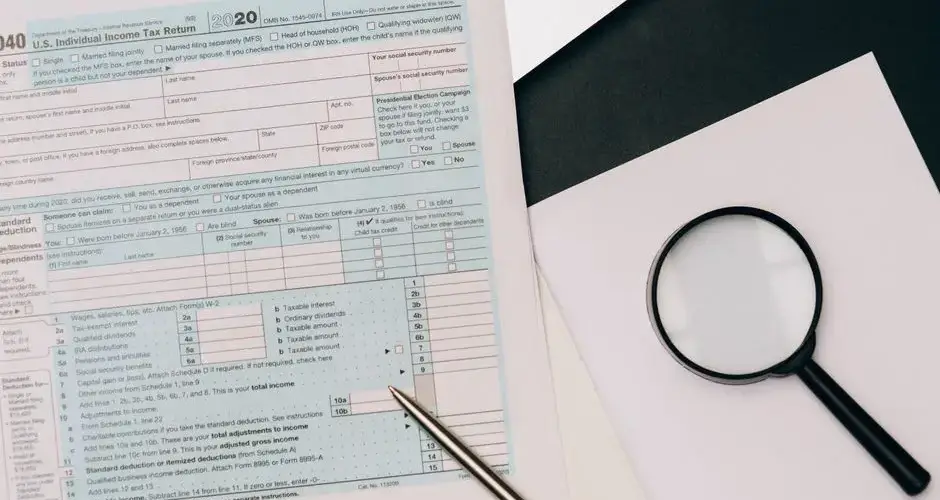 A detailed view of a tax return form with a pen and magnifying glass, perfect for financial themes.