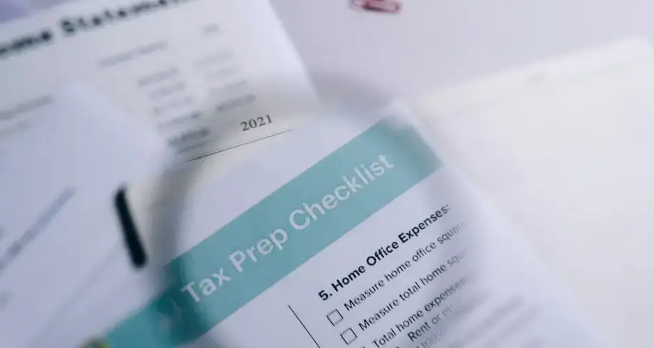 Close-up of tax preparation checklist and income statement with paperclips.