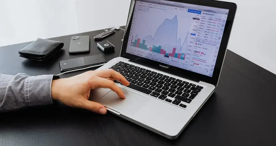 Person analyzing stock market data on a laptop at a desk.