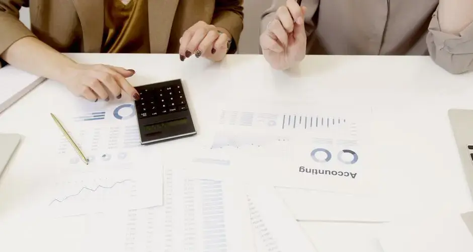 Two professionals analyzing financial documents with a calculator.