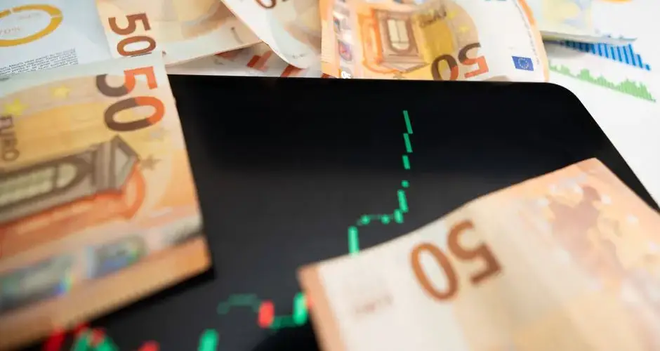 Close-up of 50 euro banknotes with a digital stock market chart on a tablet, depicting financial growth.