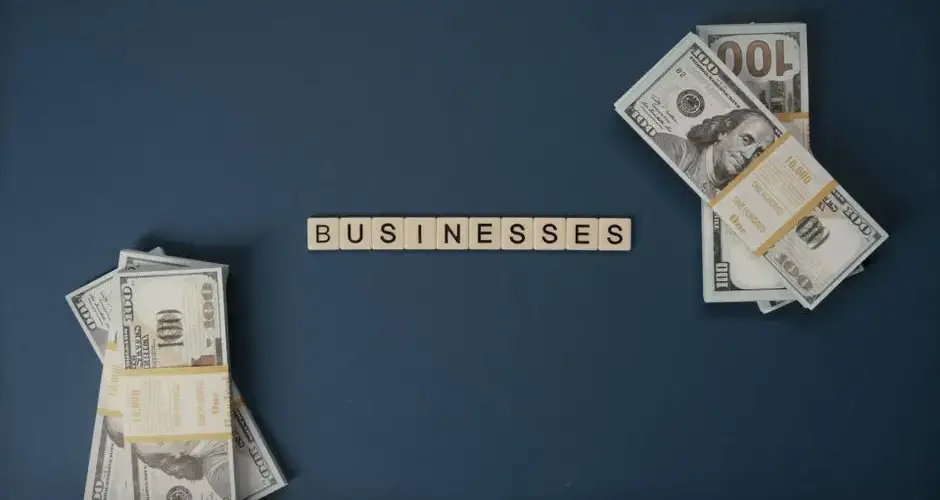 Top view of dollar bills and 'businesses' letter tiles symbolizing financial success.