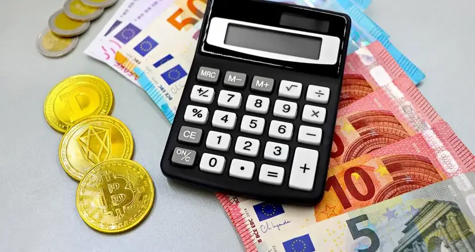 Calculator with euro banknotes and cryptocurrency coins like Bitcoin on a table.