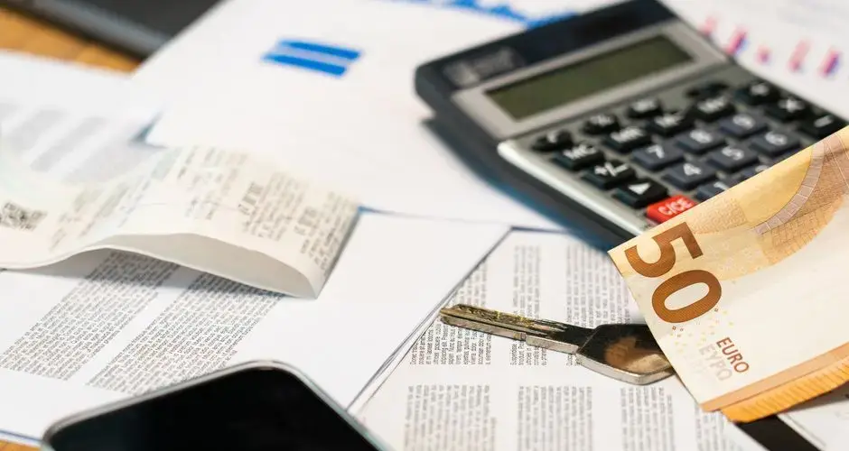 Flat lay of financial documents, euro note, calculator, smartphone, and key for budget management.