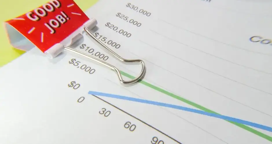 Close-up of a 'Good Job!' binder clip on a financial graph paper.