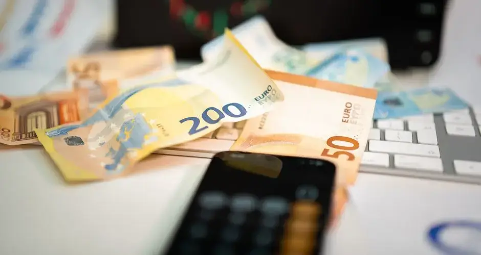 Euro banknotes and smartphone on desk, symbolizing finance and technology in business.
