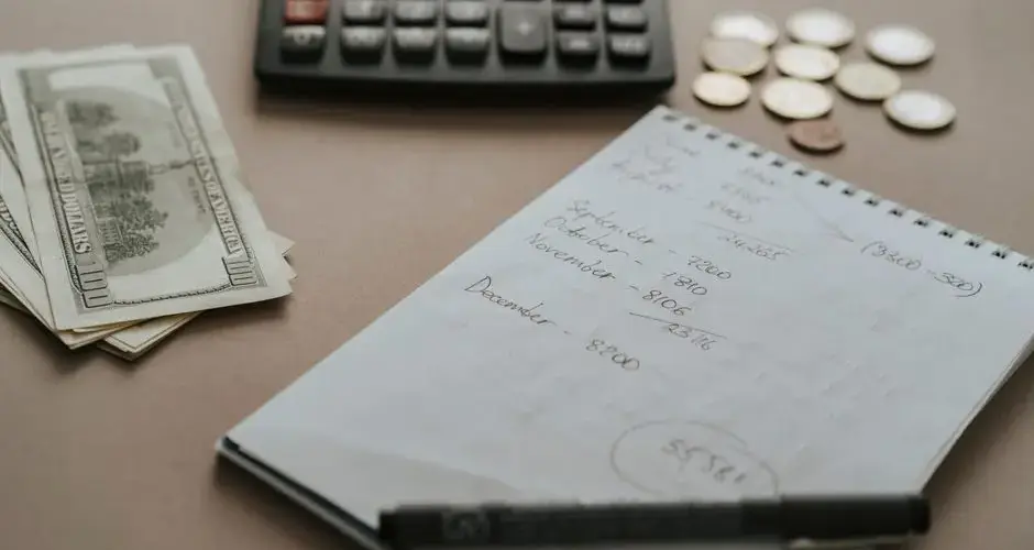 Desk setup showing calculator, cash, coins, and financial notes for budgeting.