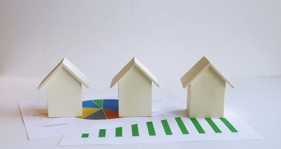 Wooden model houses on graphs depict real estate market analysis and trends.