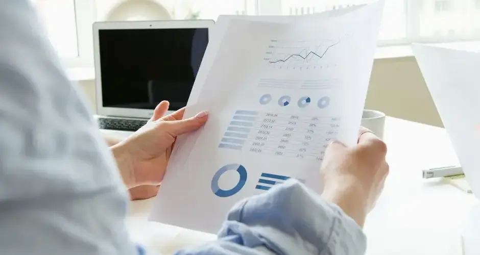 Close-up of a person analyzing business charts and graphs indoors.