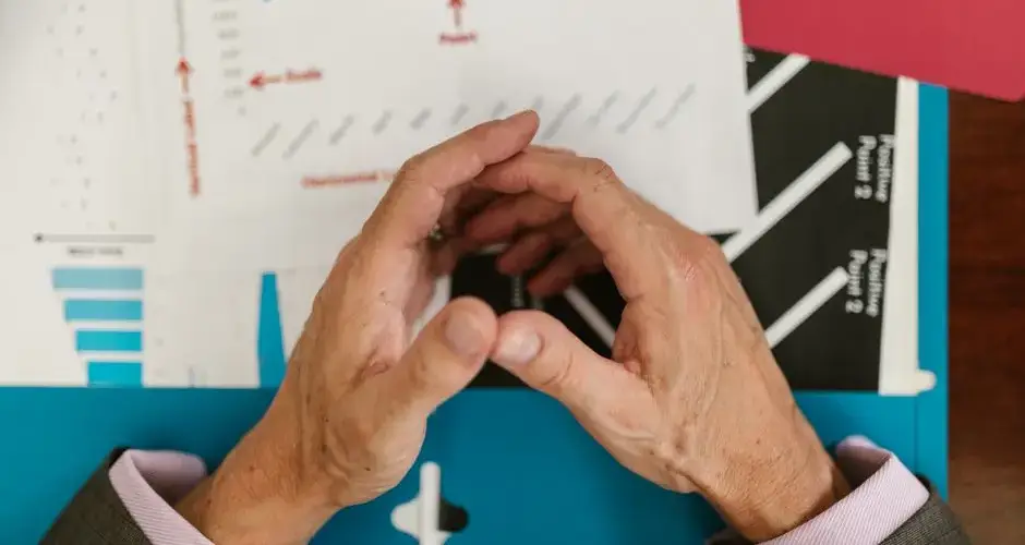 Hands examining financial graphs and charts on a wooden desk, indicative of business planning.
