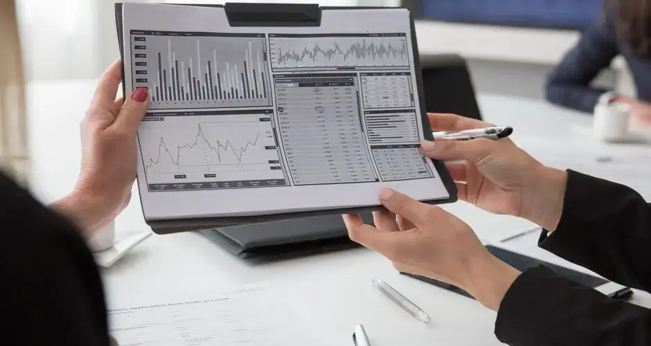 Professionals reviewing data charts on paper during a business meeting.