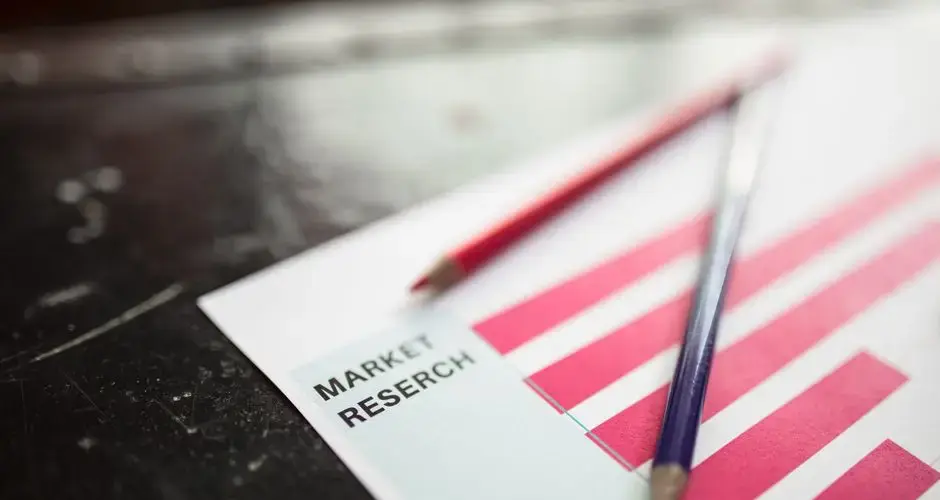Close-up of market research paper with red graph bars and pencils, emphasizing business analysis.