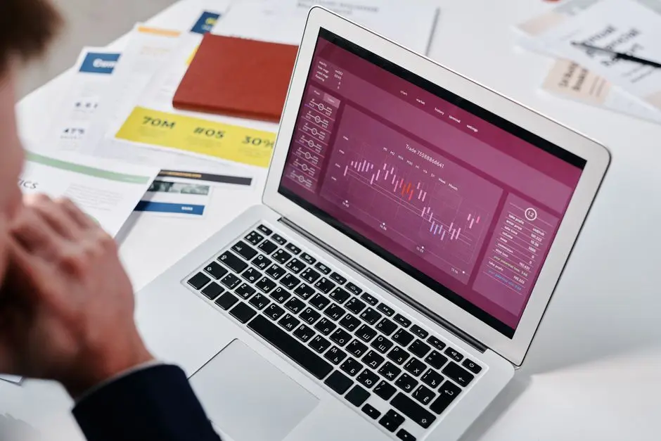 Businessperson reviewing data analytics on a laptop screen in an office setting.