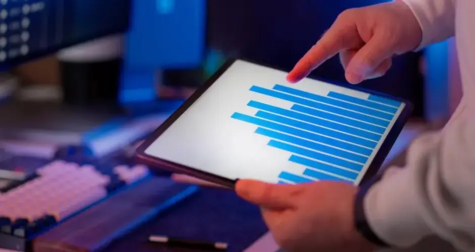 Business professional analyzing bar chart on tablet in office setting, highlighting data insights.