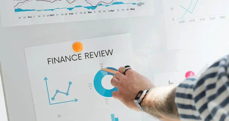 Close-up of a hand pointing to financial charts during a business review.