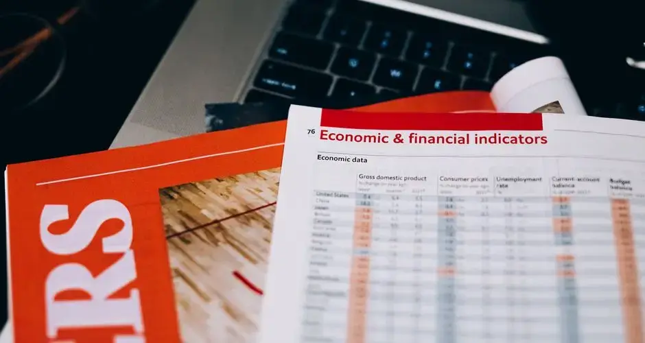 Detailed close-up of economic and financial documents on a laptop keyboard, highlighting data analytics.
