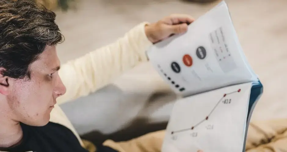 Adult man reviewing business charts in a document, focused on growth strategy.