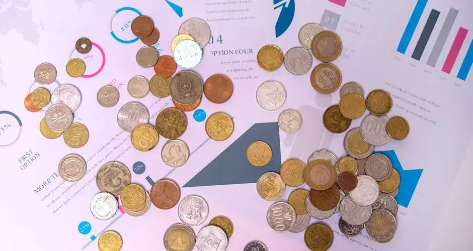 Image of various coins on financial documents with graphs and charts.