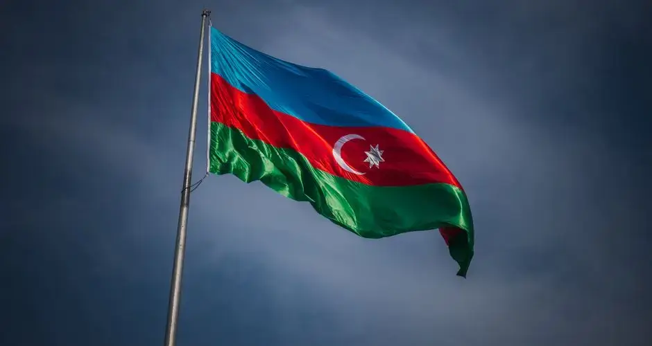 A vibrant Azerbaijani flag flutters proudly on a flagpole against a clear blue sky, symbolizing national pride.