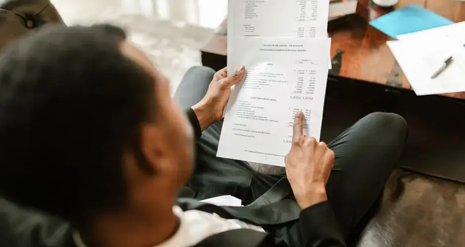 Business professional examining financial documents, focusing on analytics and paperwork in an office setting.