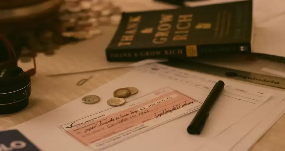 Close-up of a business desk with a check, coins, pen, and financial books, creating a financial planning vibe.