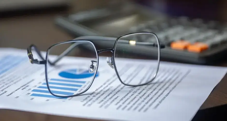 Eyeglasses on financial report with calculator in office setting, highlighting analysis.